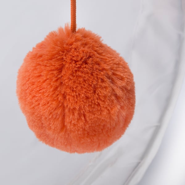 Roodachtig oranje pompon met dichte, zachte vacht en gevlochten koord tegen een witte achtergrond.