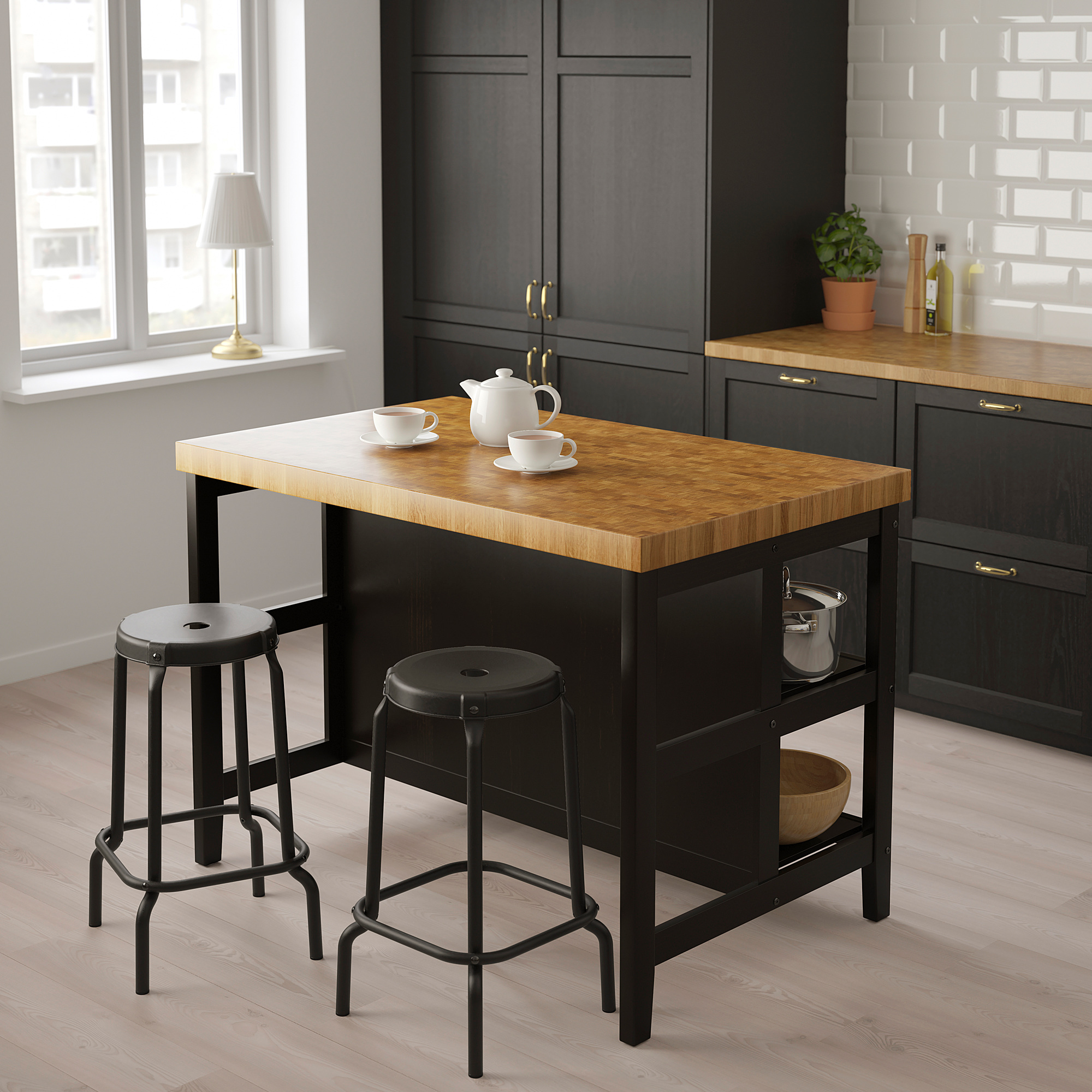 Modern VADHOLMA kookeiland met houten blad, twee krukken en theepot met kopjes.