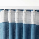 Gordijnhaken die blauwe en witte gordijnen ophangen.