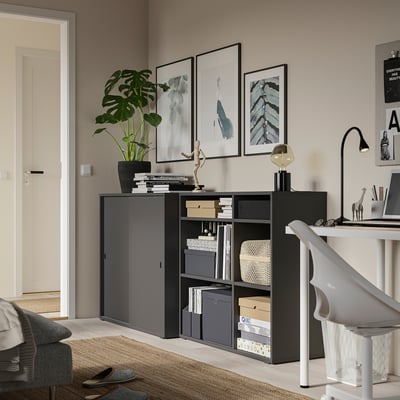 Thuiskantoor met zwarte opbergkast, bureau, planten en kunst.