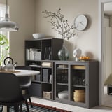 Opbergmeubel met zwarte glazen deur in de eethoek, met glazen, kommen en decoraties.