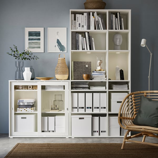 Modern kantoor aan huis met VIHALS witte opbergers, boeken, decor, rieten stoel en vloerlamp.