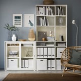 Modern kantoor aan huis met VIHALS witte opbergers, boeken, decor, rieten stoel en vloerlamp.