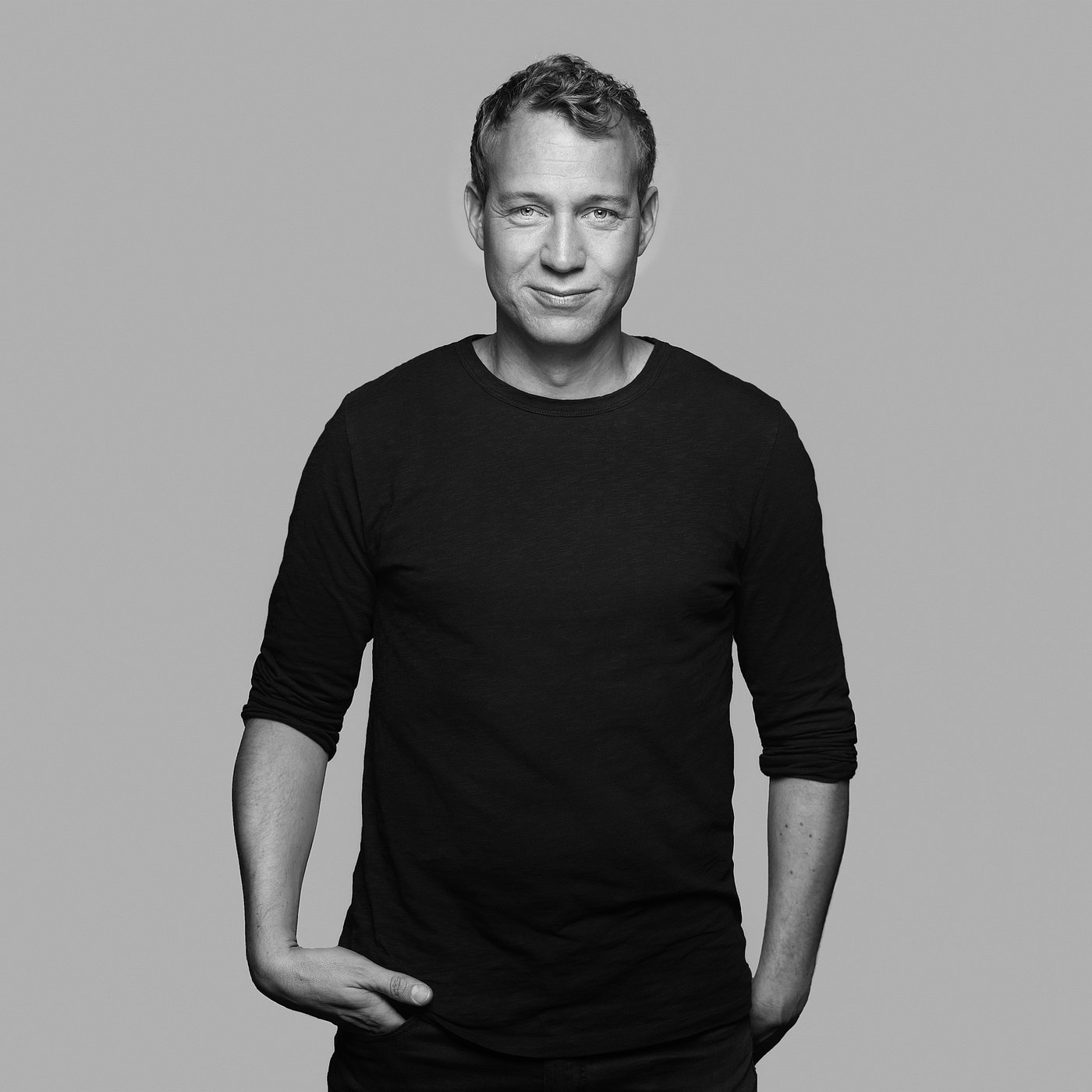 Zwart-wit portret van David Wahl met kort haar die een shirt met lange mouwen draagt, zelfverzekerd poseert.