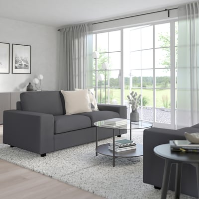 Moderne woonkamer met VIMLE grijze bank, grote ramen en gezellige inrichting.