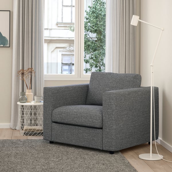 Moderne grijze VIMLE stoel, vierkante vorm. Geplaatst tussen groot raam en witte lamp, kleiner dan bijzettafel.