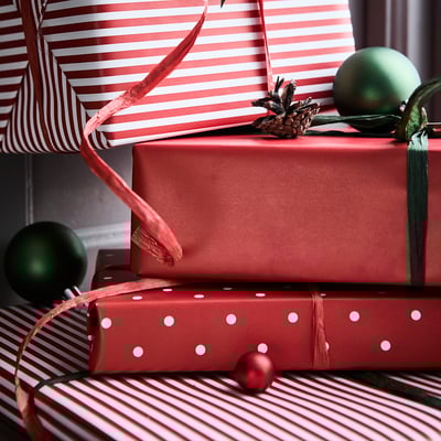 Drie rollen rood cadeaupapier: effen, gestreepte en gestippelde patronen.