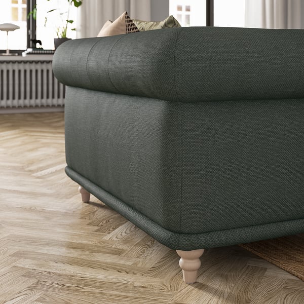 Donkergroene gestoffeerde VISKAFORS fauteuil met zachte rondingen en houten poten.