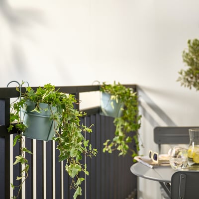 Aan balkonleuningen hangen kleine groene VITLÖK-potten.