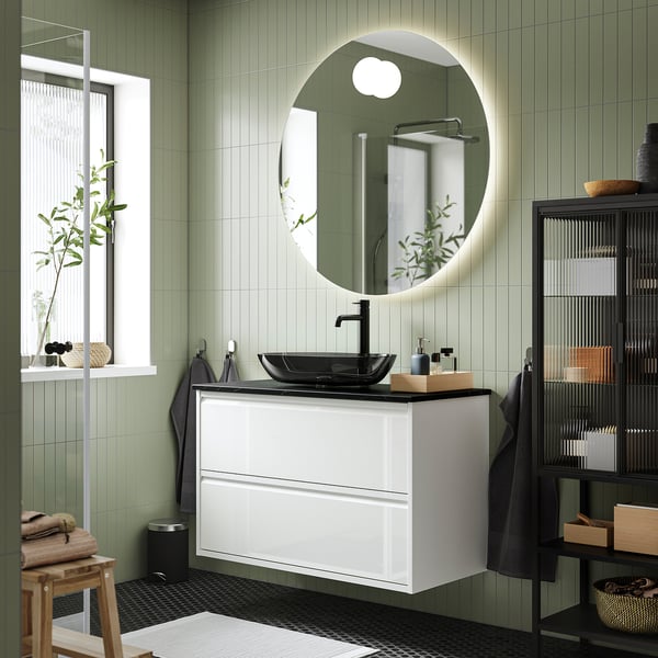 Modern bathroom with ÄNGSJÖN vanity, dark glass basin, mirror, and green tiles.