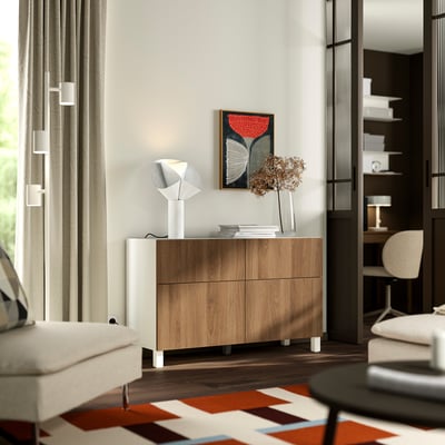 Modern living room with BESTÅ sideboard, wood drawers, white lamp, colourful rug, and beige curtains.