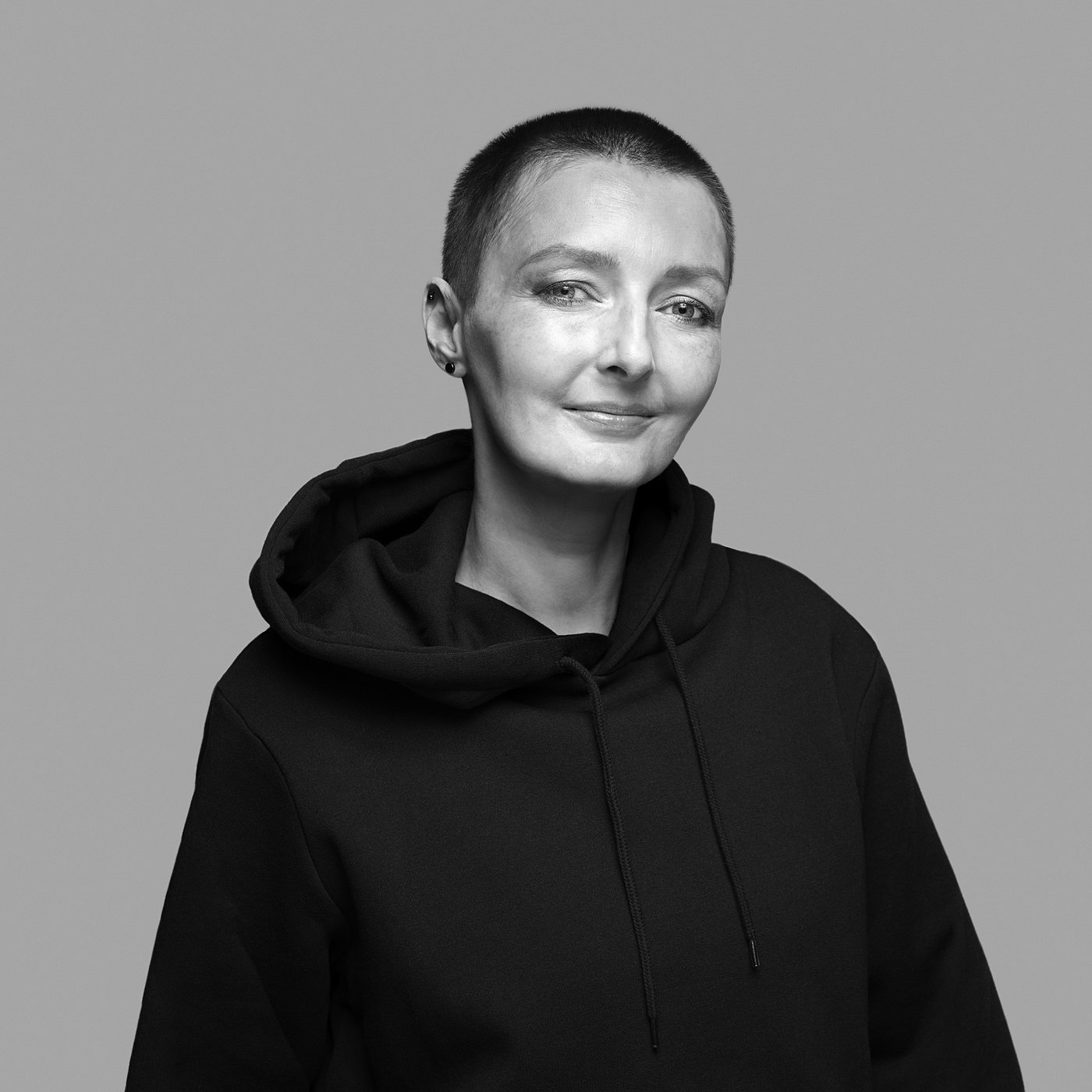 Black and white portrait of the designer with short hair, wearing a hoodie.