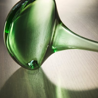 Two colourful, mouth-blown glass self-watering plant inserts; one green, one pink, both with a round top and narrow base.