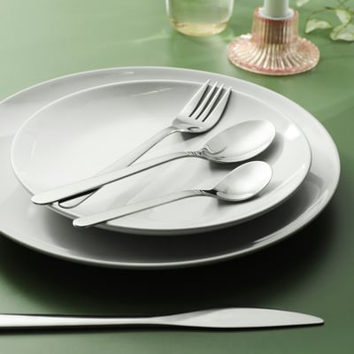 Stainless steel cutlery set - fork, knife, spoon on plates. Sleek design, shiny silver.