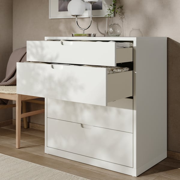 Clean white chest of drawers with multiple drawers, one open revealing inner compartment. Modern design with smooth surfaces and sleek handles.