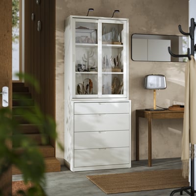 Off-white TONSTAD cabinet & chest, glass doors, wooden floor, grey wall, beige lamp.