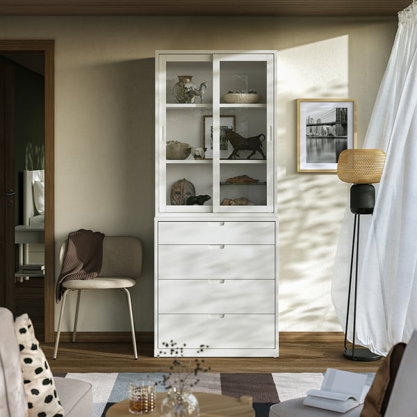 Modern living room with white TONSTAD cabinet and chair, decorative items, books, lamp, and window curtain.