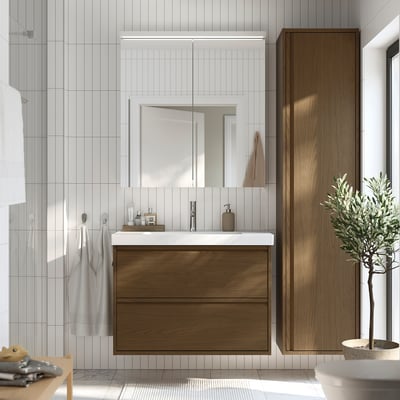 Modern bathroom with large brown oak vanity, white sink, and glass shower door. Mirror and tall cabinet included.