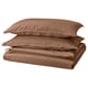 A stack of brown bed linens, including a duvet cover and pillowcases, neatly folded, made from 100% cotton.
