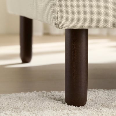 Close-up of sofa legs: smooth, dark wood finish on sturdy, round beech supports.