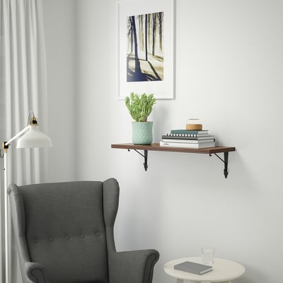 Modern room with BERGSHULT shelf, books, plant, decor, armchair, and artwork.