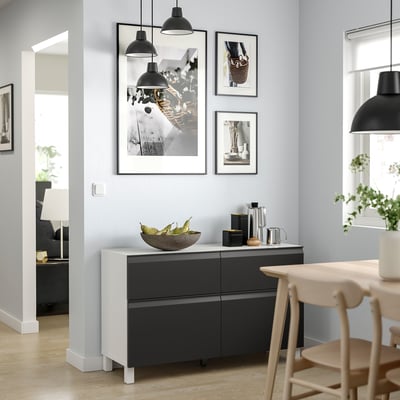 Modern room with black and white decor. A BESTÅ sideboard, pendant lights, artwork, and wooden chairs.