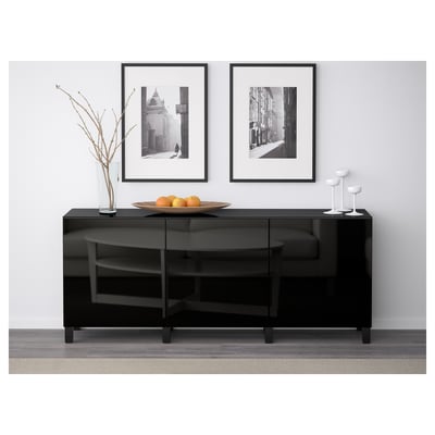 Black glossy BESTÅ sideboard with 3 doors, displaying decor items. Framed photos hang above, with a bowl of citrus and candle holders on top.