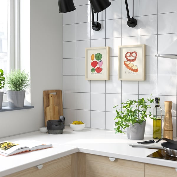 Modern kitchen with fruit posters, lamps, lemons, plants, cookbook, and cutting board.