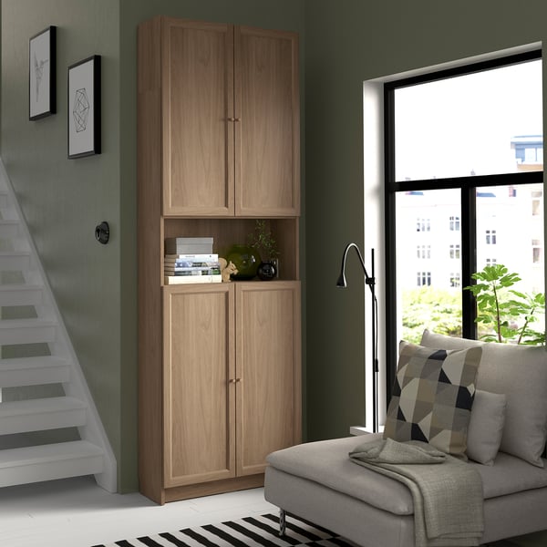 Modern room with tall wooden BILLY bookcase, grey couch, and large window.