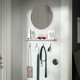 Decorative pink mirror with shelf, holding personal items, above hooks with hanging bags and umbrella.