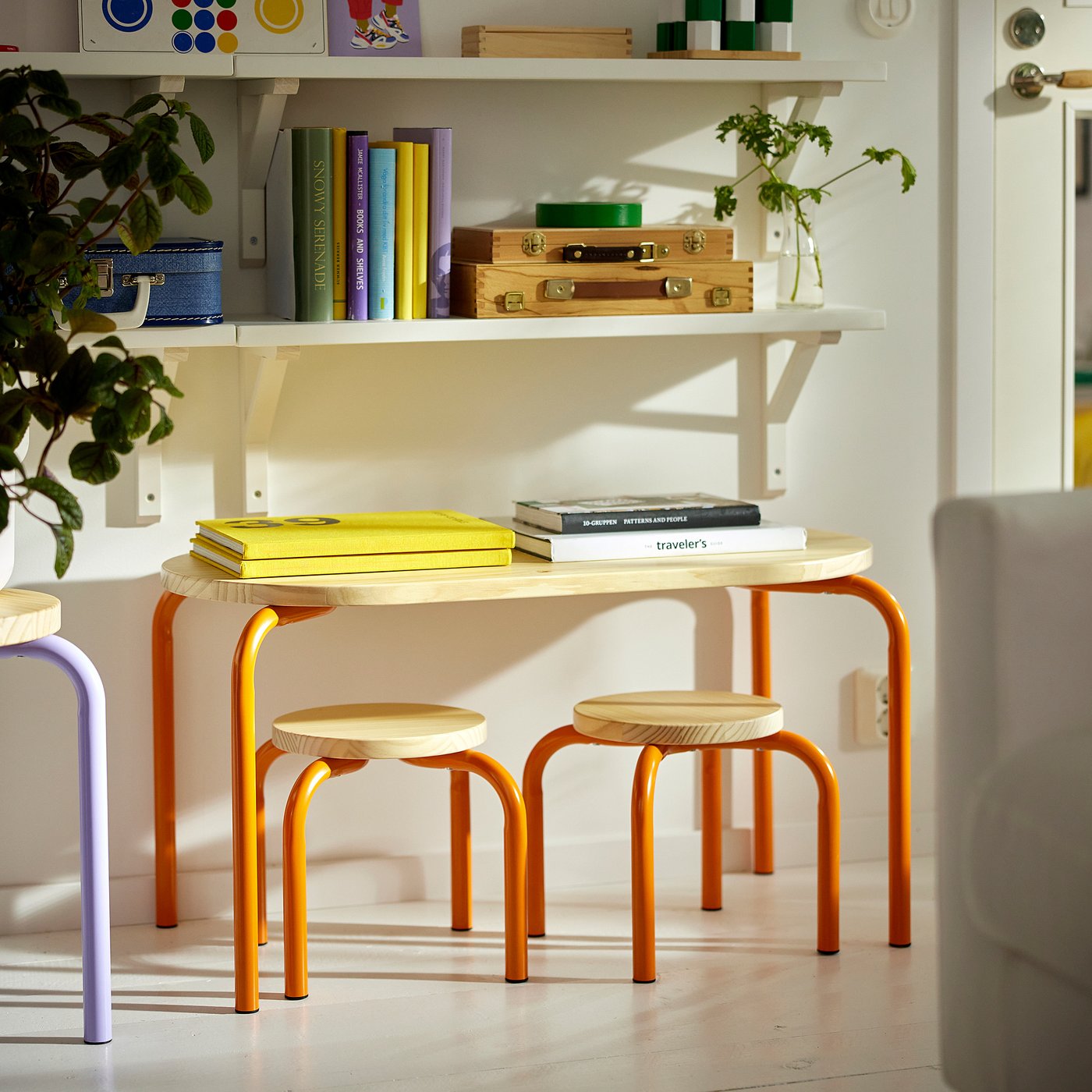 Small orange GREJSIMOJS furniture set with wooden seats and steel legs, placed under a white shelf with colourful items.