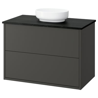 Black bathroom cabinet with round white sink, modern design.