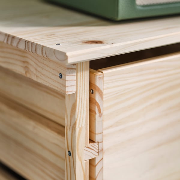A close-up of a wooden drawer joint, showing robust construction with visible screws and natural wood grain.