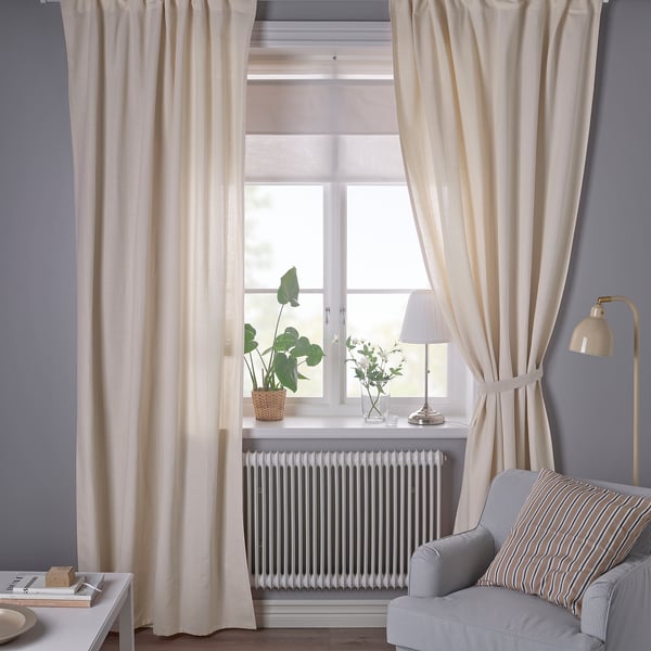 Off-white curtains hang from a tall window against a dark grey wall. A striped chair and floor lamp are below.