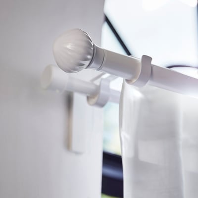 Two white ceramic finials for curtain rods, one showing attached base, featuring a ribbed, rounded shape.