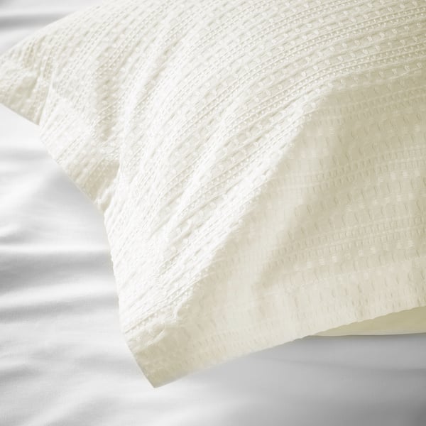 Close-up of crisp, white waffle-weave cotton bedding, showcasing its textured, breathable fabric.