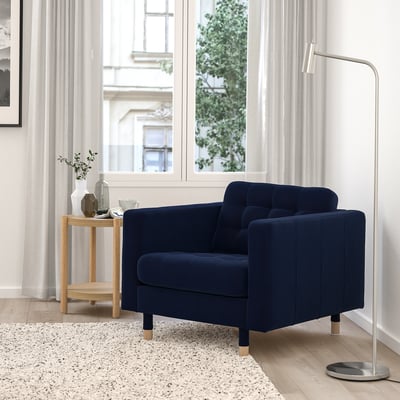 Navy blue MORABO armchair in modern living room, near window, with side table and lamp.