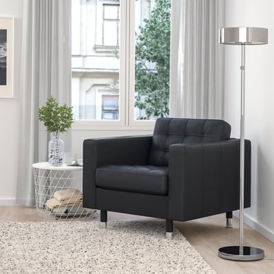 Modern black armchair in cosy living room with lamp and plant.