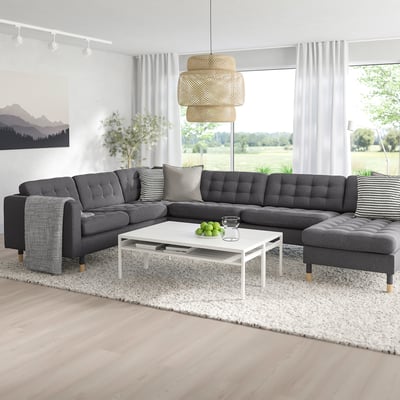 Modern living room with MORABO sectional sofa in dark grey, large windows, white coffee table, unique pendant light, and nature view outside.