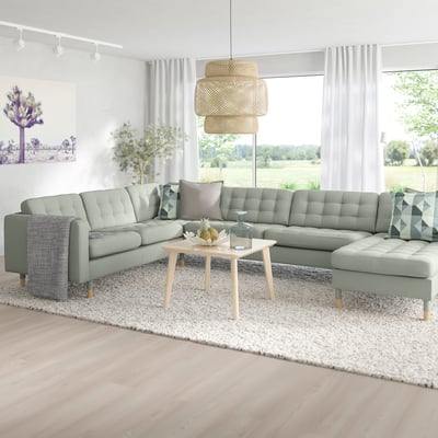 Modern living room with large, light grey, l-shaped MORABO sofa, wooden coffee table, and wicker pendant light.
