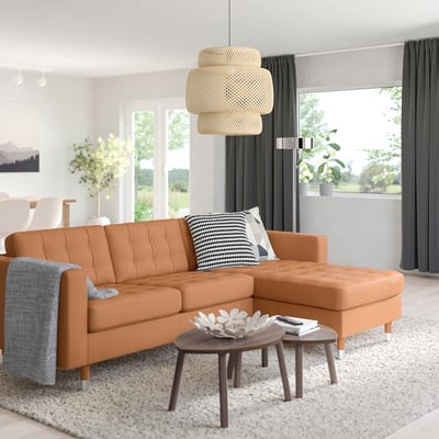 Modern living room with orange MORABO sofa, chequered pillow, pendant lamp, and patterned rug.