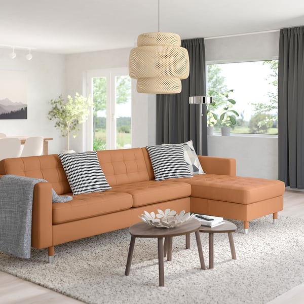 Living room with MORABO couch, pillows, rug, coffee table, vase, light, garden doors, curtains.