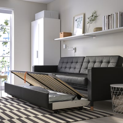 Modern living room with convertible sofa-bed, storage, and shelves.