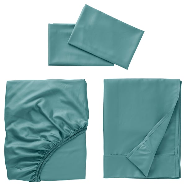 Three pieces of teal bedding: two flat sheets, one slightly crumpled with elastic, one folded neatly; all smooth, silky texture.