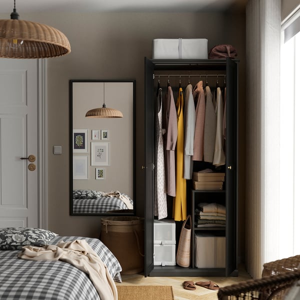 Bedroom with open wardrobe, mirror, and bed. Wardrobe holds clothes and organises shelves and hanging space.