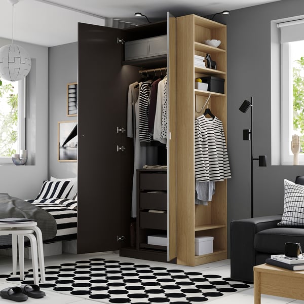 Modern open wardrobe displaying clothes; striped rug, black sandals, black door.