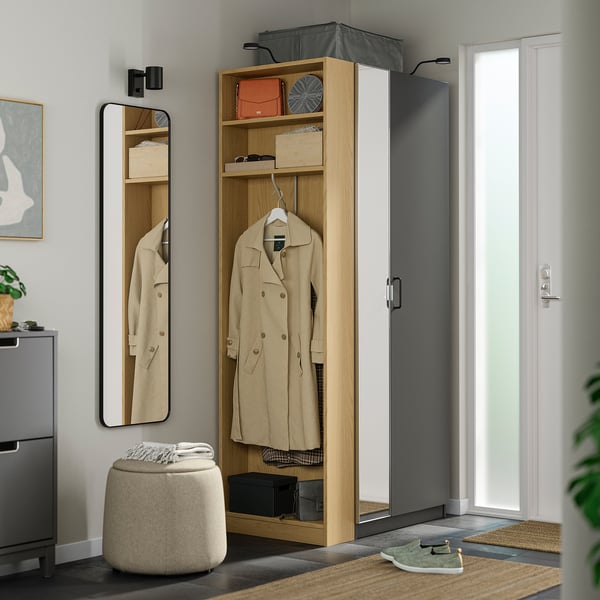 Modern entryway with tall PAX wardrobe in white & oak, reflecting mirror, beige coat, large door.