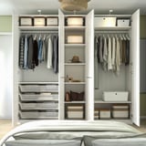Modern bedroom with PAX wardrobe, open doors showing organised clothes and storage.