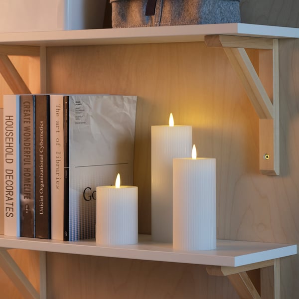 Shelf with books and led candles. Candles emit warm glow with timer function.