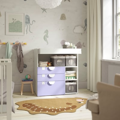 Nursery with SMÅSTAD changing table. Light purple storage drawers, white top. Soft rug, natural light. Decor with sea creatures.